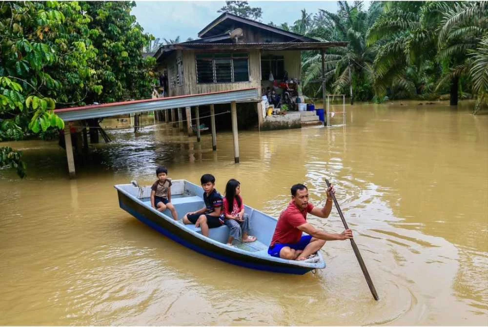 Mohd Nazrul Fadli (kanan) menaiki bot bersama anaknya untuk ke pusat pemindahan sementara (PPS) selepas kediaman mereka dinaiki air dalam gelombang kedua banjir di Terengganu.