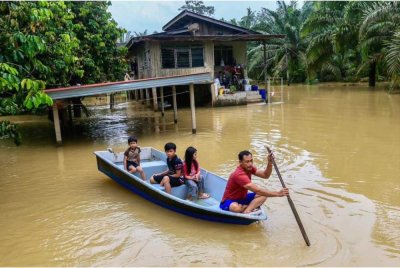 Mohd Nazrul Fadli (kanan) menaiki bot bersama anaknya untuk ke pusat pemindahan sementara (PPS) selepas kediaman mereka dinaiki air dalam gelombang kedua banjir di Terengganu.