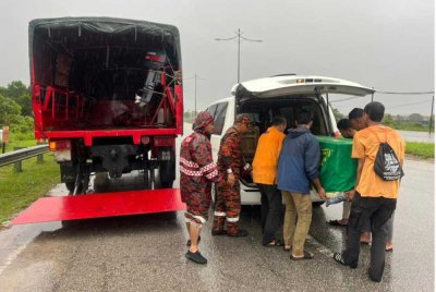 Anggota bomba bersama orang awam membantu memindahkan jenazah yang terkandas banjir ke atas lori bomba. - Foto: FB JBPM Pahang