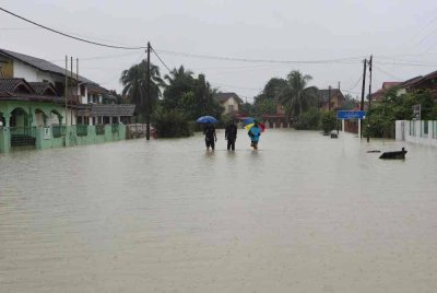 Tiga penduduk terpaksa meredah air banjir yang menenggelami Taman Guru susulan limpahan Sungai Belat ketika tinjauan pada Rabu. Foto Bernama 