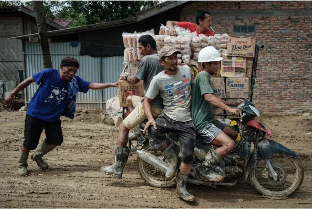 Beberapa penduduk mengangkut bekalan bantuan penting untuk komuniti terjejas banjir.