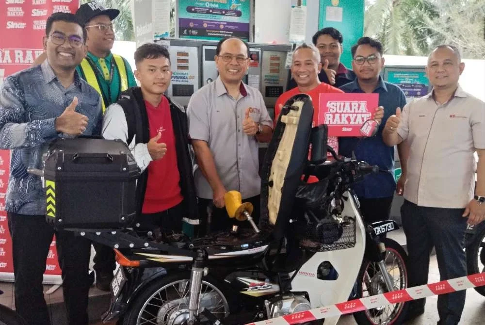 Ali (tengah) mengisi minyak motosikal milik seorang pelajar UTM sebagai simbolik perasmian Program Isi Minyak Motosikal Percuma.