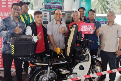 Ali (tengah) mengisi minyak motosikal milik seorang pelajar UTM sebagai simbolik perasmian Program Isi Minyak Motosikal Percuma.