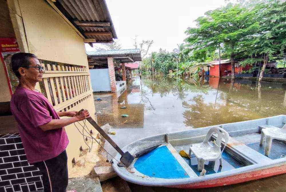 Kasim menggunakan bot untuk berulang alik dari rumah di kampung Sungai Isap dinaiki air sejak Rabu. Foto Sinar Harian 
