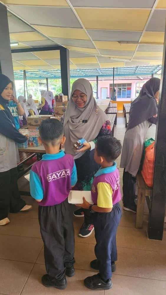Seorang guru memberikan sarapan pagi kepada murid-murid Sekolah Kebangsaan Bayas, Langkawi.