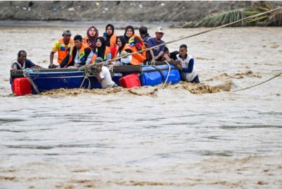 Penduduk terpaksa menaiki bot untuk menyeberangi sungai selepas jambatan yang menghubungkan perkampungan mereka musnah dibawa arus deras banjir.