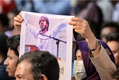 Seorang aktivis memegang poster Sharif Osman Hadi, pemimpin kanan kumpulan protes pelajar Inqilab Mancha di Dhaka. Foto AFP