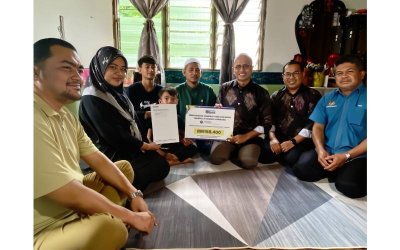 Ahmad Dasuki (tiga,kanan) menyerahkan surat kelulusan dan replika kad manfaat perlindungan takaful Simpan SSPN Plus kepada keluarga Allahyarhamah Rohaya di Chiku 3, Gua Musang.