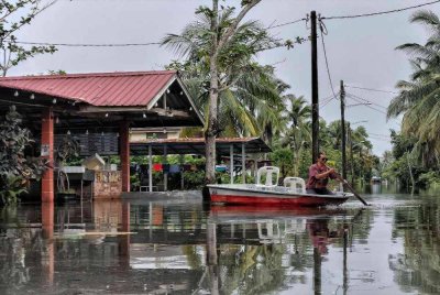 Kasim sedang mendayung bot selepas kawasan itu dinaiki air sedalam satu meter susulan hujan lebat beberapa hari lalu. Foto Sinar Harian 