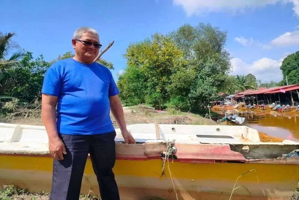 Zabri menunjukkan keadaan sampan miliknya yang rosak akibat bencana yang melanda di Batu 8, Lekir di sini pada Sabtu.