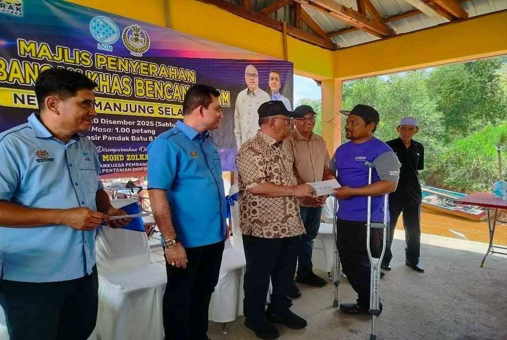 Mohd Zolkafly (tiga dari kiri) menyampaikan sumbangan kepada Muhammad Haris sempena Majlis Penyerahan Sumbangan Khas Bencana Alam Nelayan Manjung Selatan di Jeti Lembaga Kemajuan Ikan Malaysia (LKIM) Pasir Pandak Batu 8 Lekir di sini pada Sabtu.