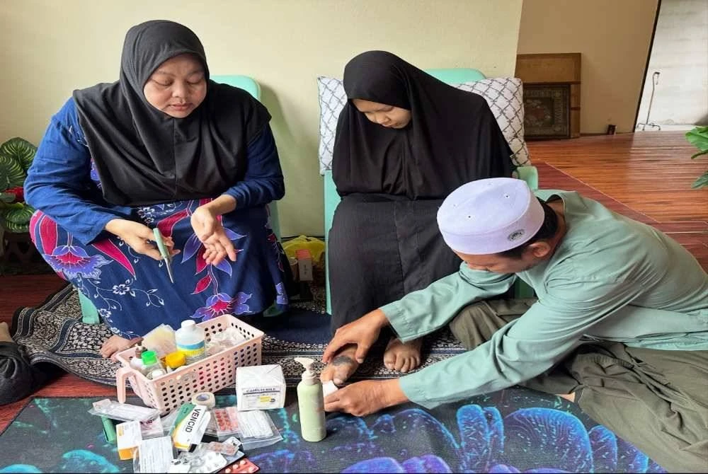 Siti Fauziah (kiri) dan Syukri (kanan) mencuci luka pada jari kaki Nur Syafina (tengah). 
