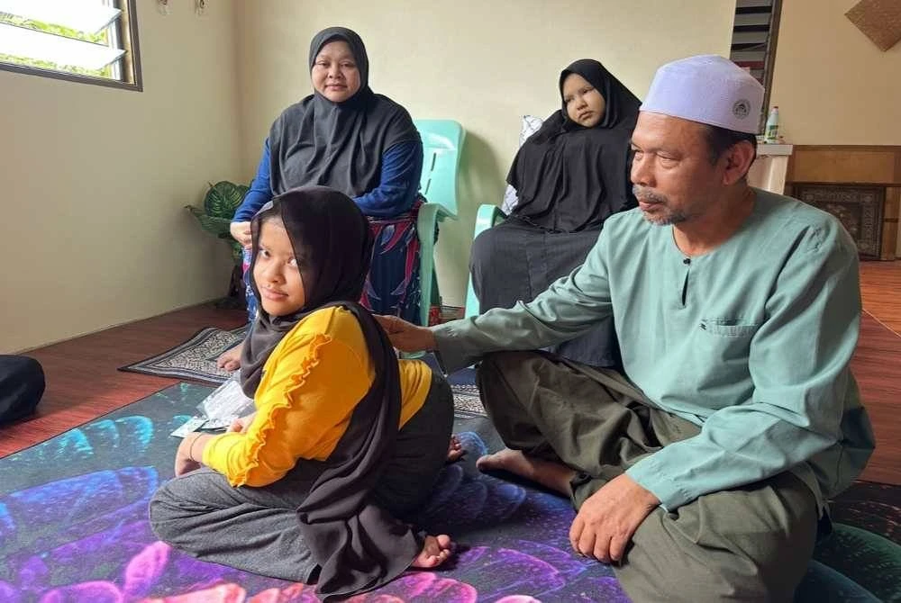 
Syukri (kanan) menunjukkan belakang Nur Syaza Azahra (kiri) yang bengkok. 