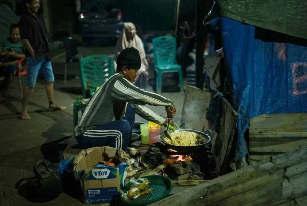 Seorang lelaki menyediakan nasi goreng untuk mangsa di pusat penempatan sementara.
