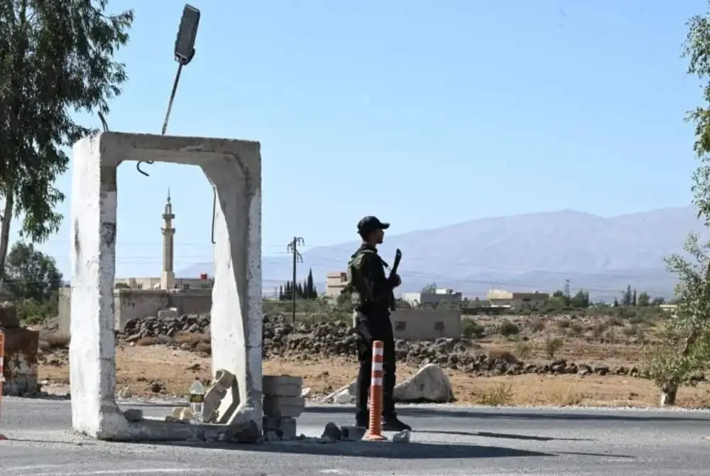 Anggota keselamatan Syria berkawal di luar kawasan bekas kem tentera berhampiran Quneitra di selatan Syria. Foto: AFP