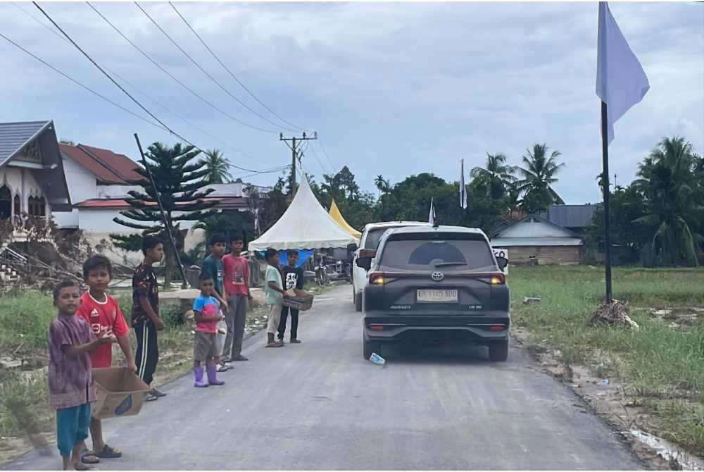 Kanak-kanak di Mukim Langkahan, Aceh Utara yang terjejas akibat banjir besar melanda 26 November lepas, meminta bantuan dari kenderaan-kenderaan asing yang melewati kawasan perkampungan mereka. - Foto: Bernama