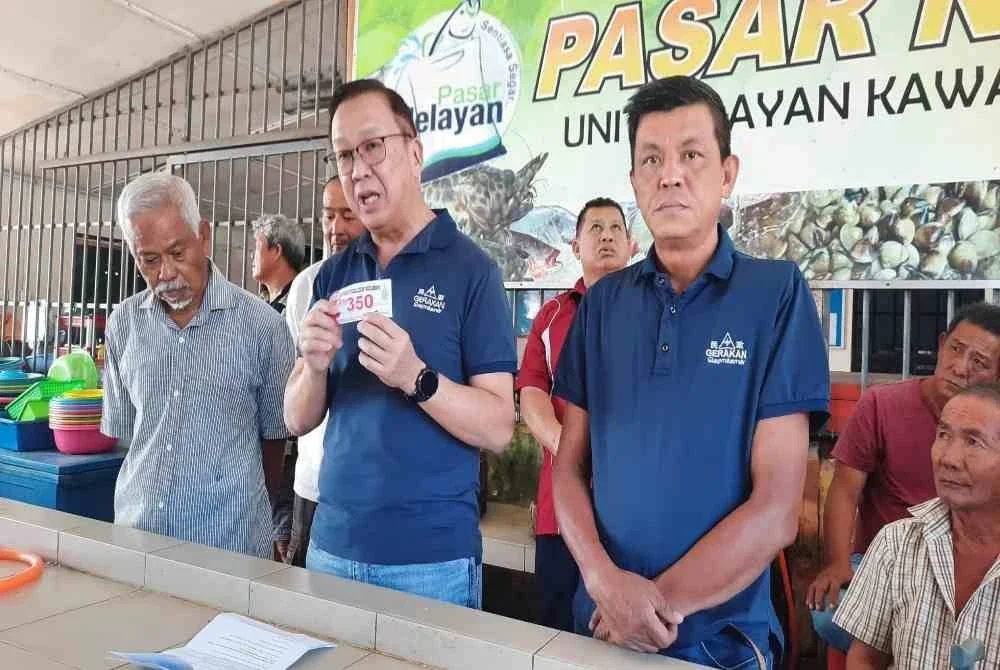 Dominic (tengah) menunjukkan kupon bernilai RM350 yang dikeluarkan Pejabat Exco namun ada nelayan yang tidak dapat menebusnya.