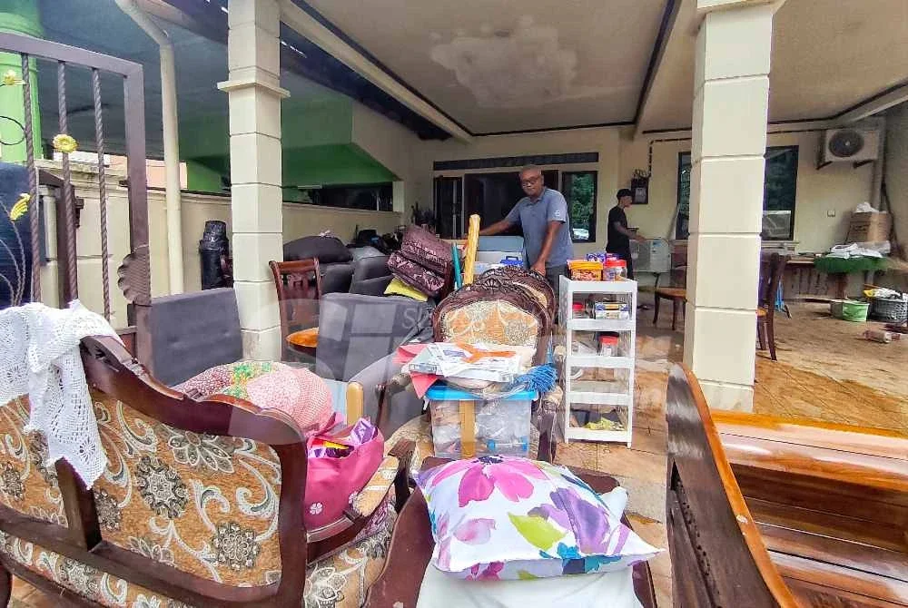 Muhammad Tashrif menjemur kerusi dan perabot lain di hadapan rumahnya selepas banjir surut sepenuhnya. 