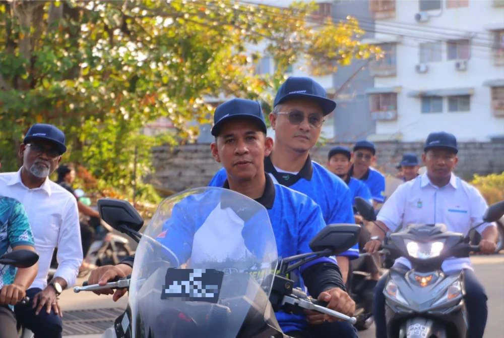 Mohamad membonceng motosikal ketika program Kembara Santuni Asnaf di Sungai Ara.