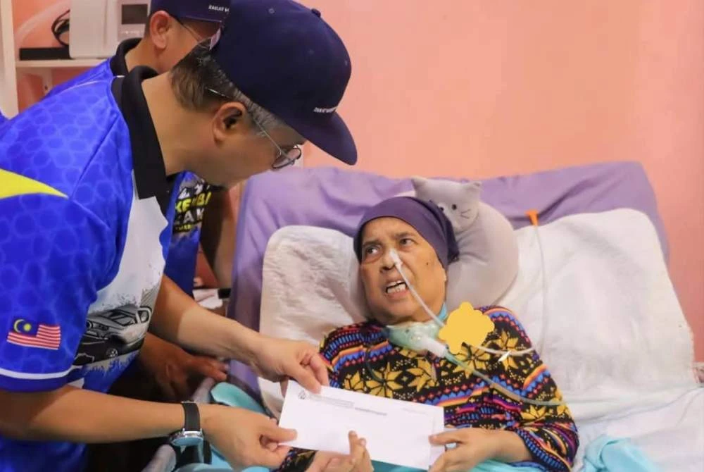 Mohamad menyampaikan sumbangan kepada penerima ketika program Kembara Santuni Asnaf di Sungai Ara pada Ahad.