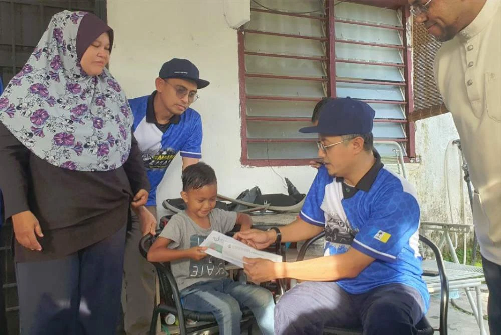 Mohamad menyampaikan sumbangan kepada penerima ketika program Kembara Santuni Asnaf di Sungai Ara pada Ahad.