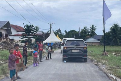 Kanak-kanak di Mukim Langkahan, Aceh Utara yang terjejas akibat banjir besar melanda 26 November lepas, meminta bantuan dari kenderaan-kenderaan asing yang melewati kawasan perkampungan mereka. - Foto: Bernama