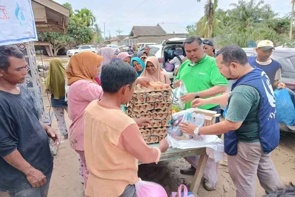 Mas Imran (dua dari kanan) menyerahkan kanvas dan pek makanan panas kepada mangsa banjir.