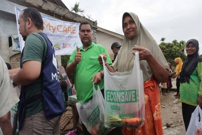 Mas Imran (tengah) menyerahkan kanvas dan pek makanan panas kepada mangsa banjir.