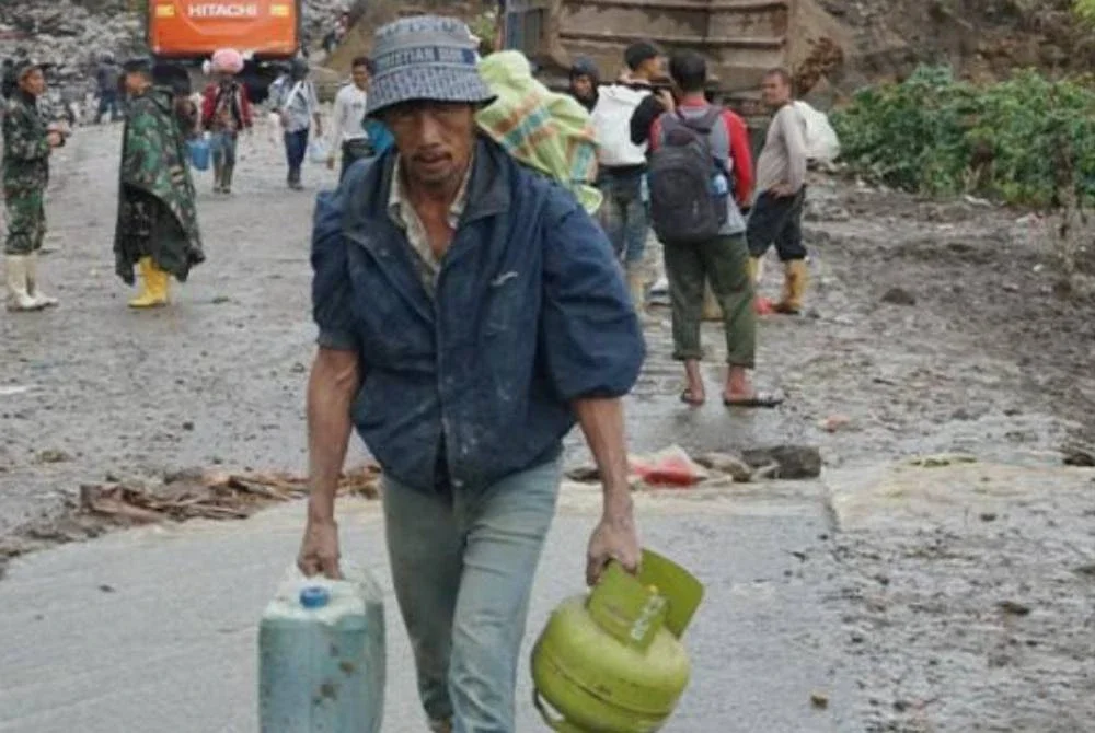 Seorang lelaki membawa pulang tabung gas dan BBM. Foto Agensi