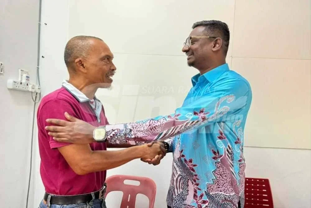 Noor Sallehin (kiri) bersalaman dengan Kumaresan selepas perbincangan mengenai kandang lembu tidak berlesen di Pejabat ADUN Batu Uban, George Town pada Rabu.