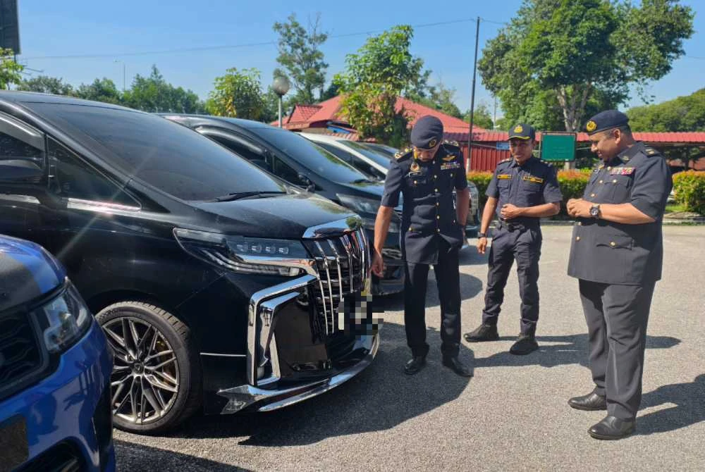 Hanif Yusabra (kiri) menunjukkan antara kenderaan mewah yang disita.