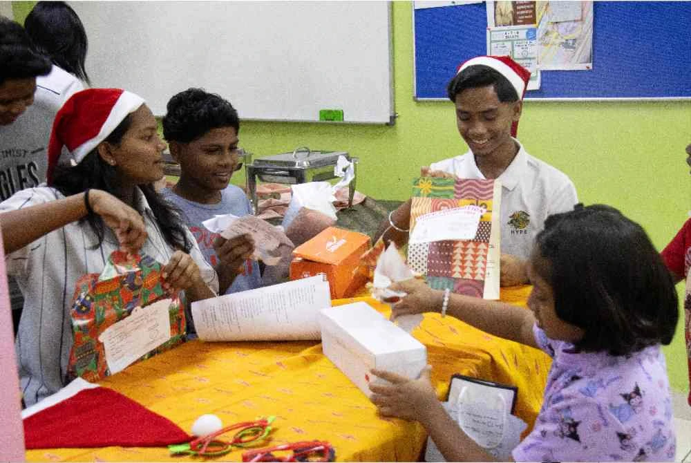Kanak-kanak pusat jagaan berkenaan membuka bungkusan hadiah Krismas mereka, sambil tersenyum riang.