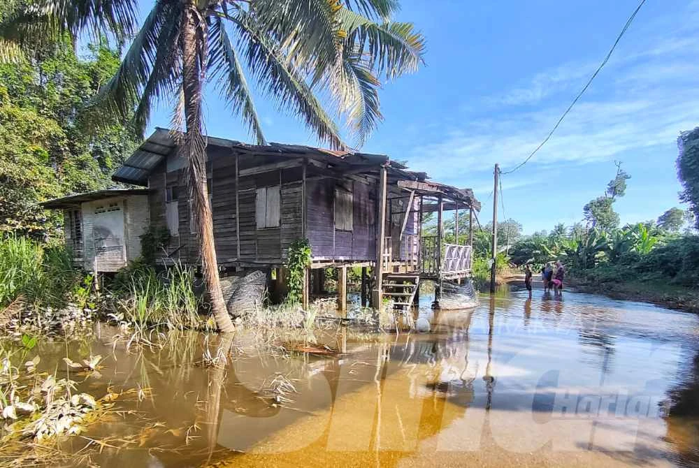 Beberapa penduduk mengharungi air banjir untuk ke rumah masing-masing di Kampung Temai Tengah pada Rabu.