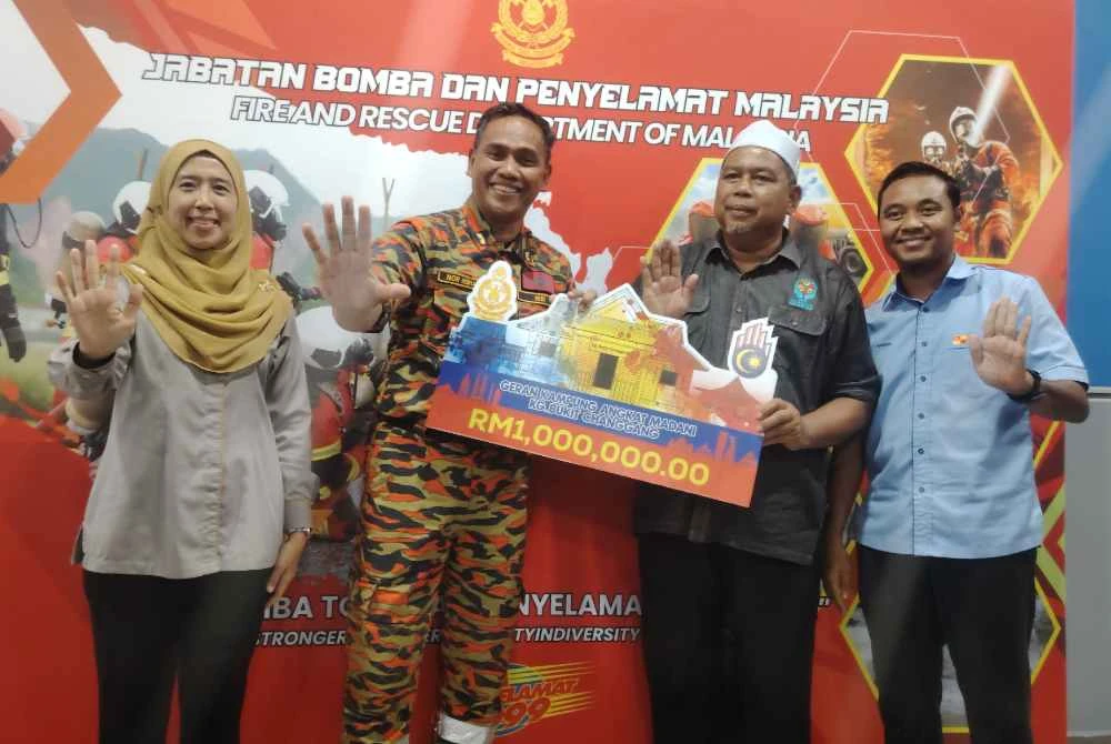 Nor Hisham (dua dari kiri) menunjukkan replika geran RM1 juta Kampung Angkat Madani Kampung Bukit Changgang pada Rabu.