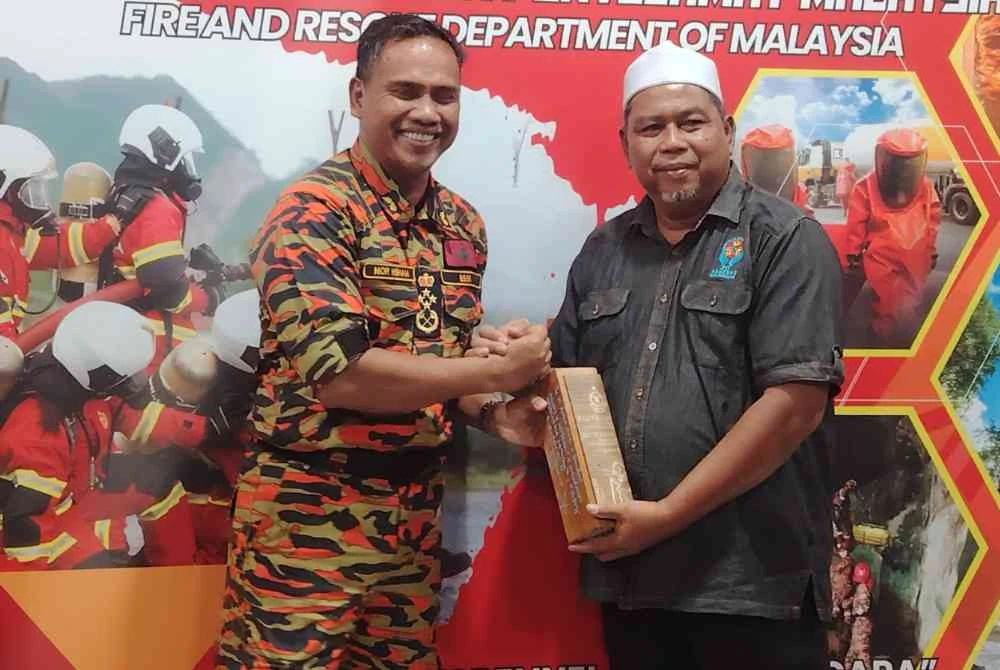 Nor Hisham memberikan cenderamata kepada Mohd Alias semasa Majlis Penyerahan Projek Kampung Angkat Madani Kampung Bukit Changgang JBPM pada Rabu.