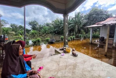 Zawiyah bersama cucunya melihat keadaan di kawasan rumah mereka yang masih digenangi air hampir seminggu.