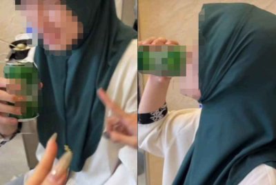 Tangkap layar rakaman video seorang individu memakai tudung sambil minum minuman keras yang tular di media sosial.