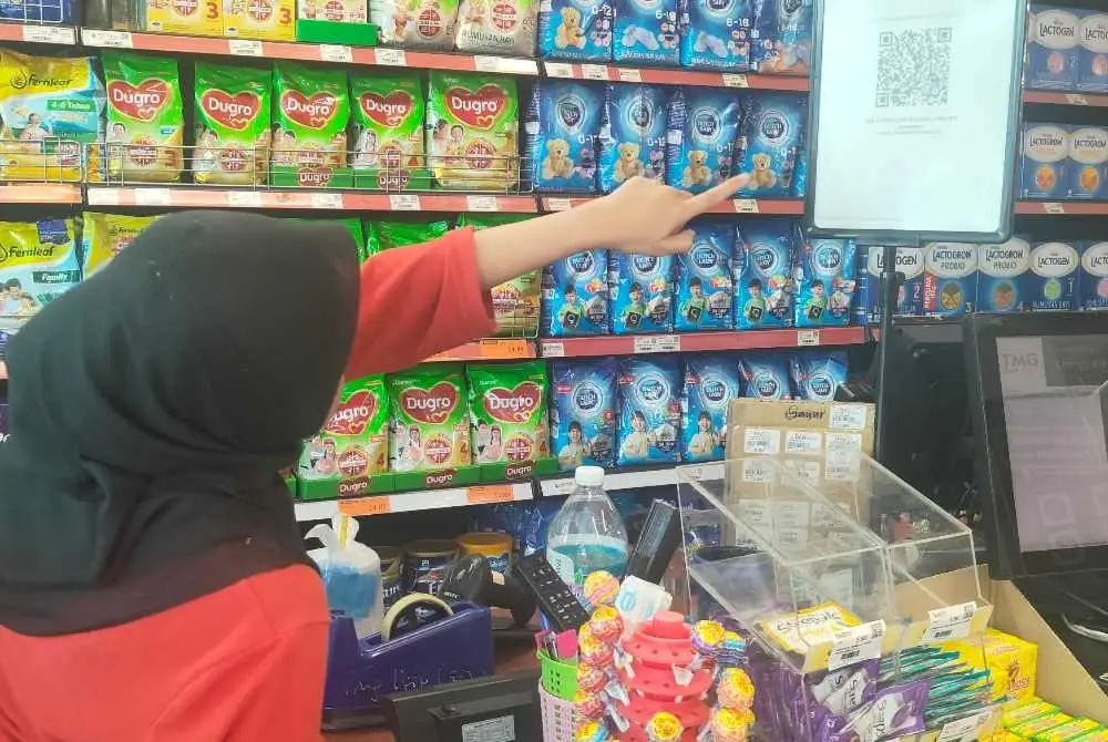 Tuan Nor Nilam Sari menunjukkan kod QR eCOSS yang disediakan di premisnya.