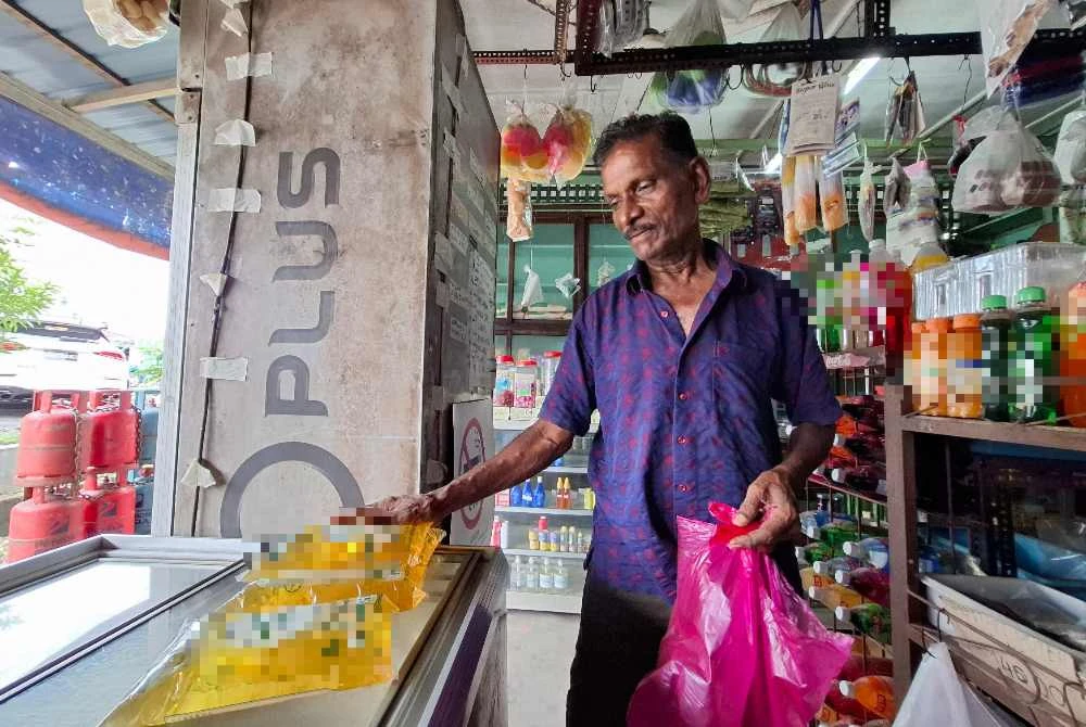 Munusamy menunjukkan bekalan minyak masak bersubsidi yang dijual di premisnya.