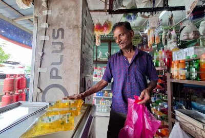 Munusamy menunjukkan bekalan minyak masak bersubsidi yang dijual di premisnya.