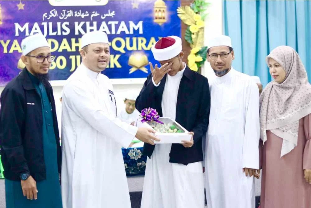 Ahmad Fikri (tiga dari kanan) bersama ibu bapanya tidak dapat menahan sebak semasa menerima penghargaan daripada Najmuddin (dua, kiri) semasa majlis khatam syahadah al-Quran 30 juzuk di MTM Panchor, Pengkalan Chepa di Kota Bharu. Foto MTM