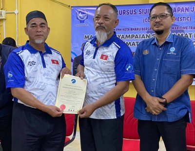 Nik Mohd Kamal (tengah) menyampaikan sijil kepada nelayan yang mengikuti Kursus Jurumudi di LKIM Kuala Besar, Kota Bharu pada Jumaat.