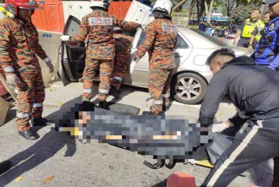 Anggota bomba mengeluarkan mayat mangsa dari dalam kereta.