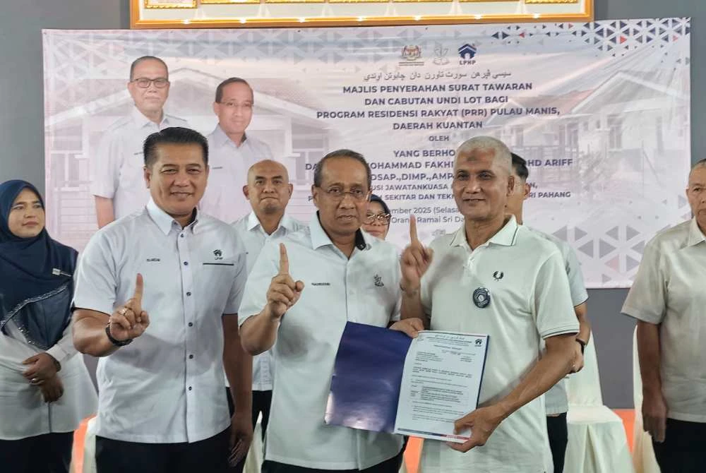 Mohammad Fakhruddin (tengah) menyerahkan surat tawaran kepada salah seorang penerima pada majlis penyerahan surat tawaran Residensi Rakyat Pahang (RRP) di Dewan Orang Ramai Kampung Sri Damai di sini pada Selasa. - Foto Sinar Harian.
