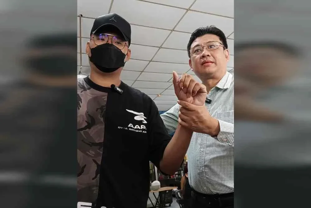 Andrew Chen (kanan) menunjukkan tangan mangsa yang cedera akibat dipukul ahli sindiket.