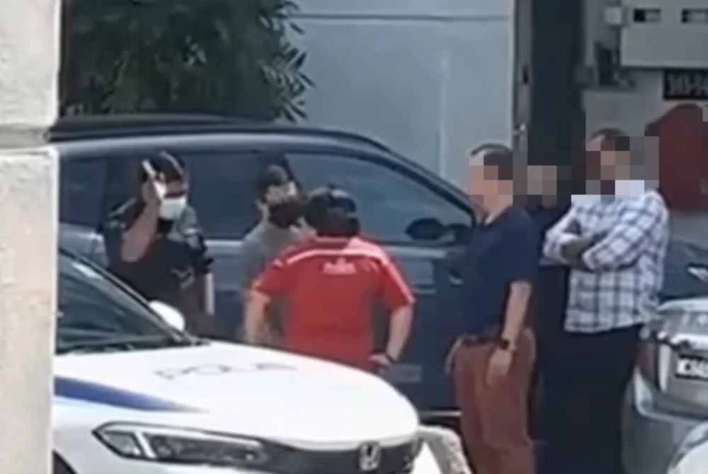 Tangkap layar menunjukkan seorang wanita dilihat memaki hamun dan meludah anggota polis.