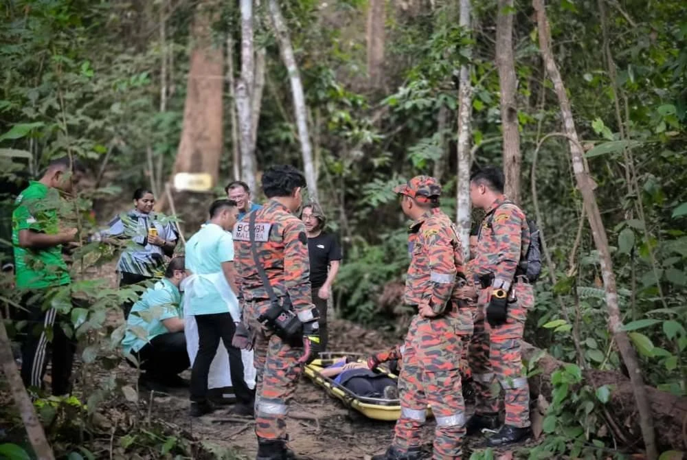 Anggota penyelamat memberikan rawatan awal kepada mangsa yang didapati pengsan ketika mendaki Bukit 300 Trail Teluk Batik di sini pada Rabu.