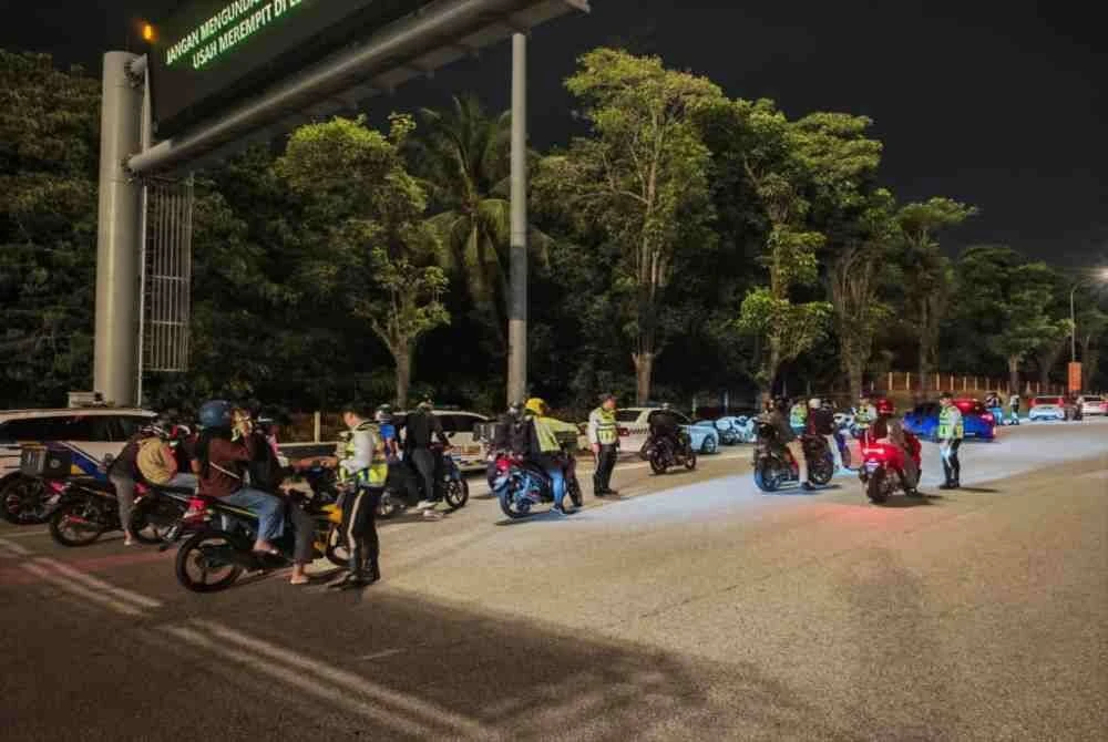 Anggota polis memeriksa penunggang motosikal dalam Op Ambang Tahun Baharu, pada Khamis.