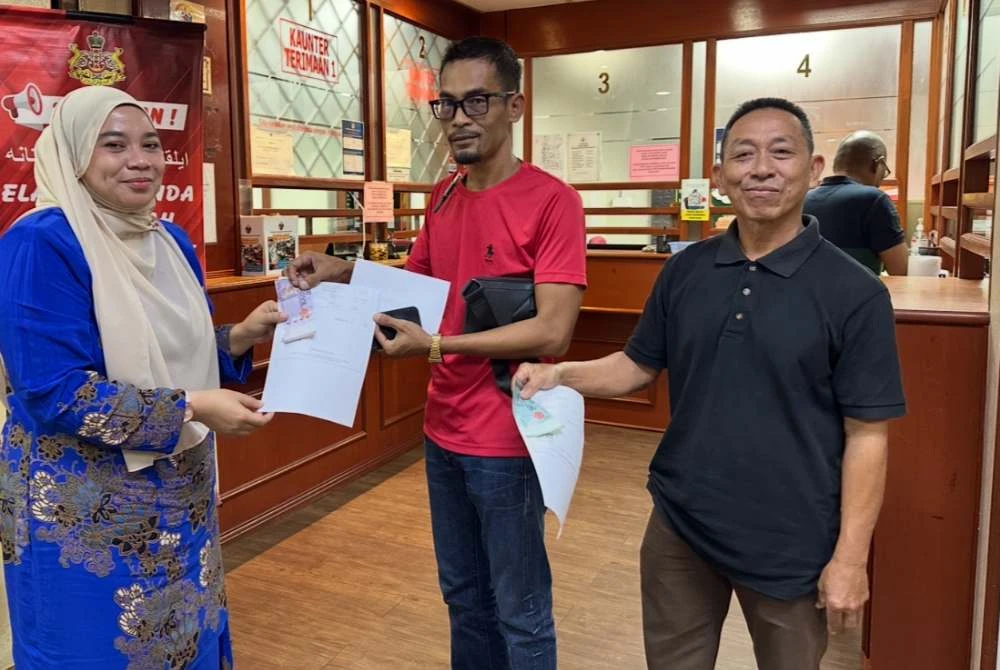 Ahmad Fauzan (tengah) menyerahkan borang permohonan kepada kakitangan PTG.