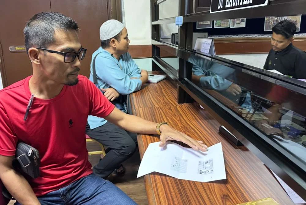 Ahmad Fauzan (kiri) membuat urusan permohonan di kaunter PTG.